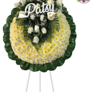 Hermosa corona fúnebre de pompos blanco con bordes verde de hojas de caucho verde con un arreglo floral en forma de V con rosas blancas y Gibson