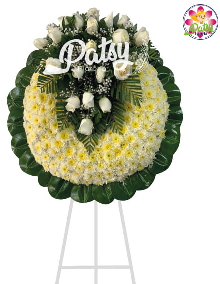 Hermosa corona fúnebre de pompos blanco con bordes verde de hojas de caucho verde con un arreglo floral en forma de V con rosas blancas y Gibson