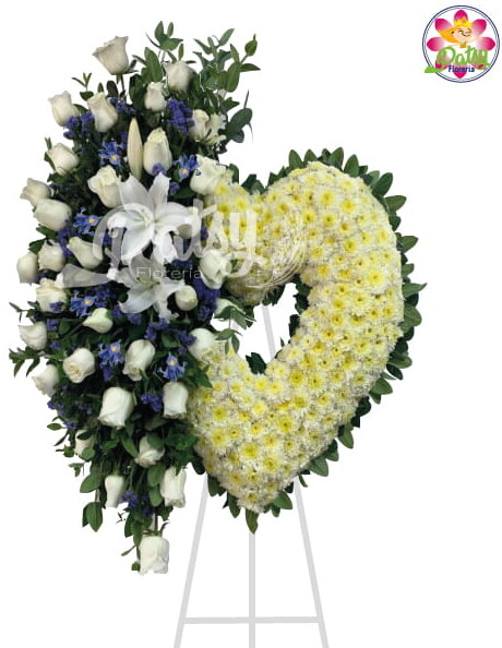 Es un corazón armado con flores (pompos naturales) con un arreglo floral al costado con Iris, rosas y lirios blancos y fino follaje verde de 2 metros de altura aprox sobre un parante (trípode) pintado en dorado.